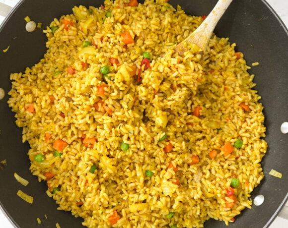 pot of cooked nigerian fried rice with a wooden spoon