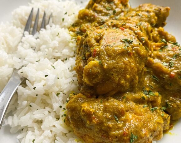 nigerian curry chicken in a white bowl with white rice and a silver fork